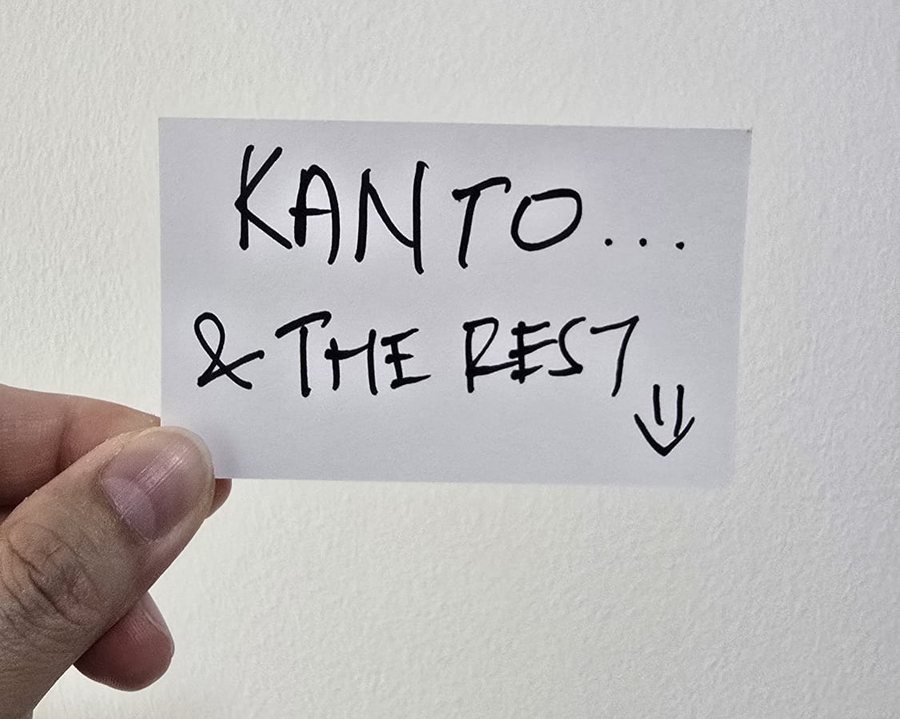 A handwritten note reading 'Kanto... & the rest', held up in front of a wall